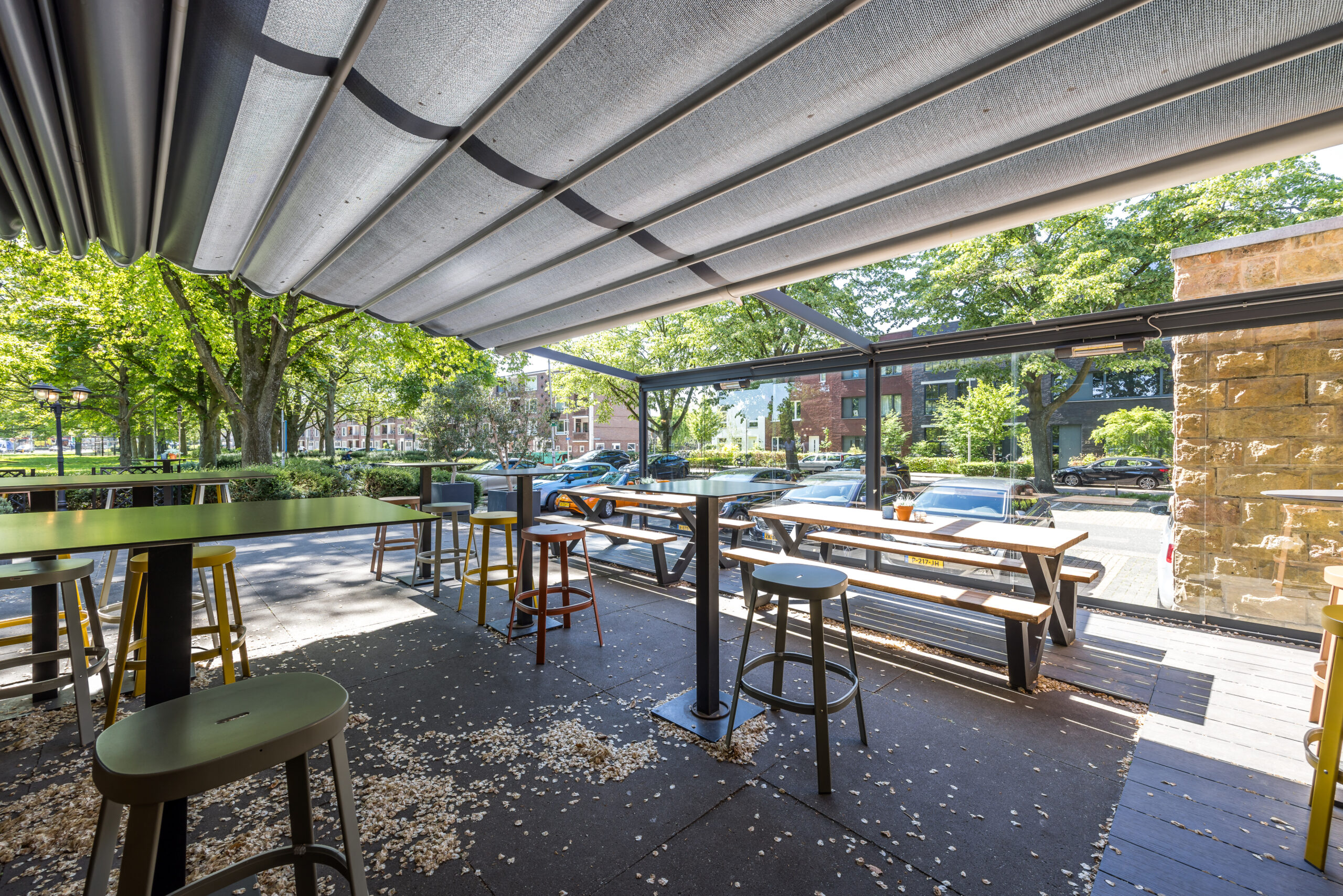 Terras van restaurant 18 bij Element Offices in Utrecht met tafels en stoelen, omringd door bomen en geparkeerde auto's.