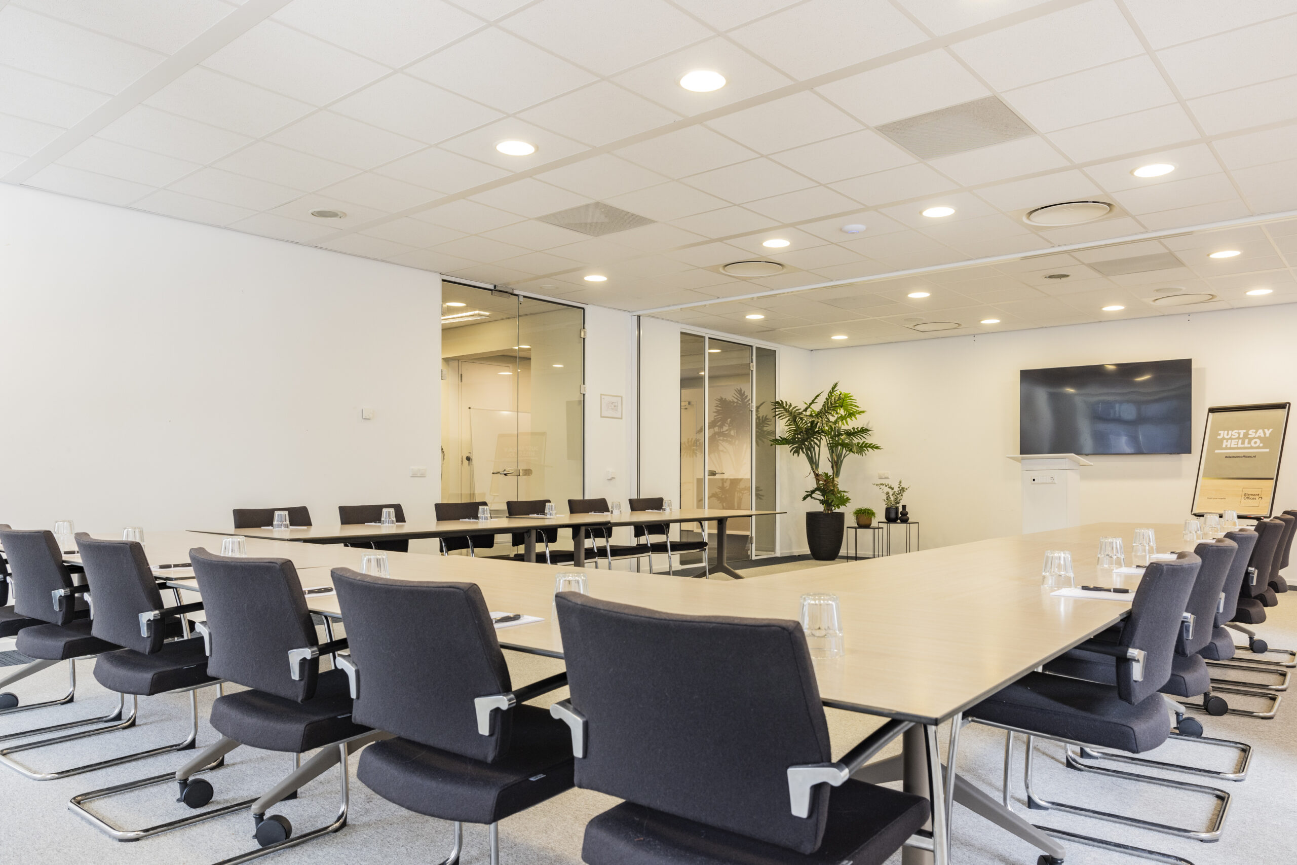 Een moderne vergaderruimte met een U-vormige tafelopstelling en zwarte stoelen in een kantoor in Rotterdam.