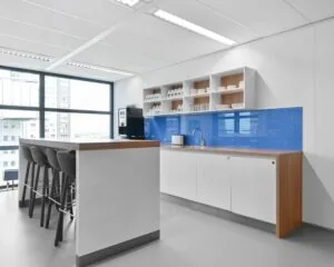 Moderne pantry in een kantoorruimte aan de Weena 209 in Rotterdam met bar, barkrukken en blauwe achterwand.