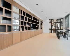 Moderne kantoorruimte aan Weena 209 in Rotterdam met open wandkasten, hoge tafels en grote ramen.