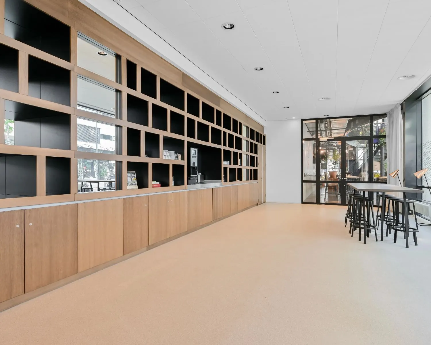 Moderne kantoorruimte aan Weena 209 in Rotterdam met open wandkasten, hoge tafels en grote ramen.
