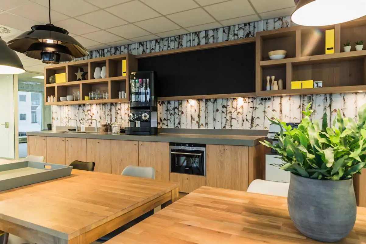 Moderne kantoorkeuken met houten kasten, koffiemachine en sfeervolle berkenboom-behang.