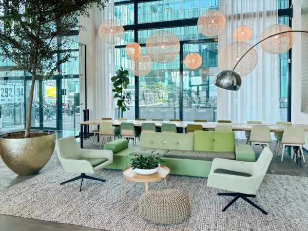 Een moderne, stijlvolle lounge met groene meubels en hanglampen in een ruime omgeving.