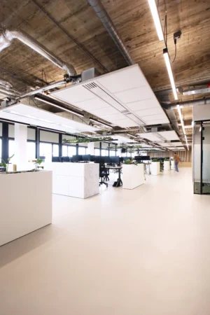 Een modern en ruim kantoor met open werkplekken, planten en een industrieel plafond.
