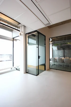 Een modern kantoorinterieur met glazen wanden en een vergaderruimte met stoelen.