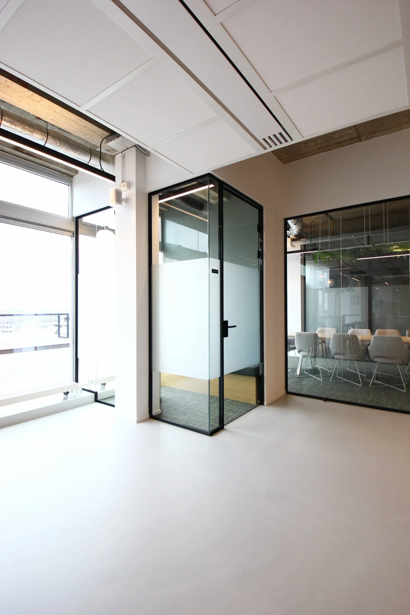 Een modern kantoorinterieur met glazen wanden en een vergaderruimte met stoelen.
