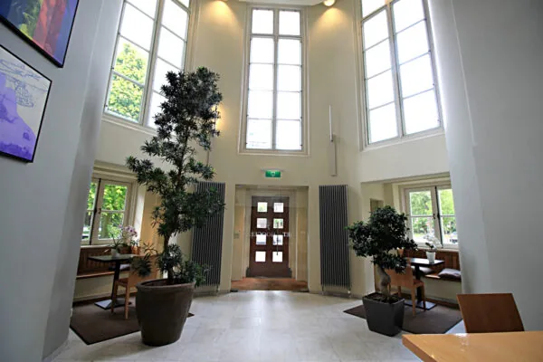 Lichte en hoge entreehal van Museumlaan 39343675 met grote ramen, planten en zitplekken bij de ramen.