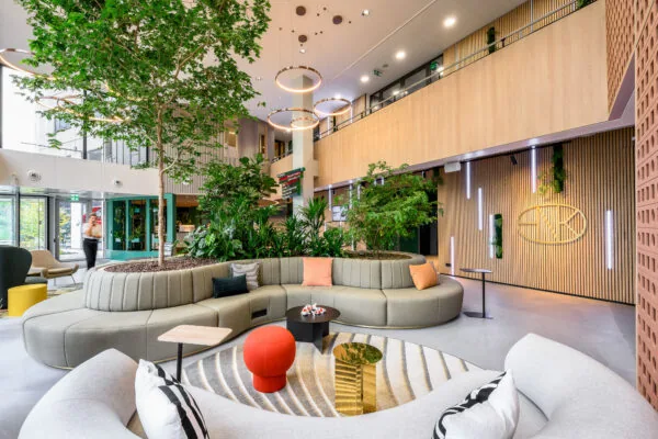 Moderne en ruime lobby met groen ingerichte zithoek, natuurlijk licht en houten wanddetails.