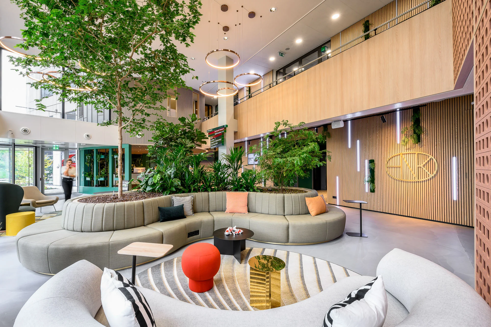 Moderne en ruime lobby met groen ingerichte zithoek, natuurlijk licht en houten wanddetails.