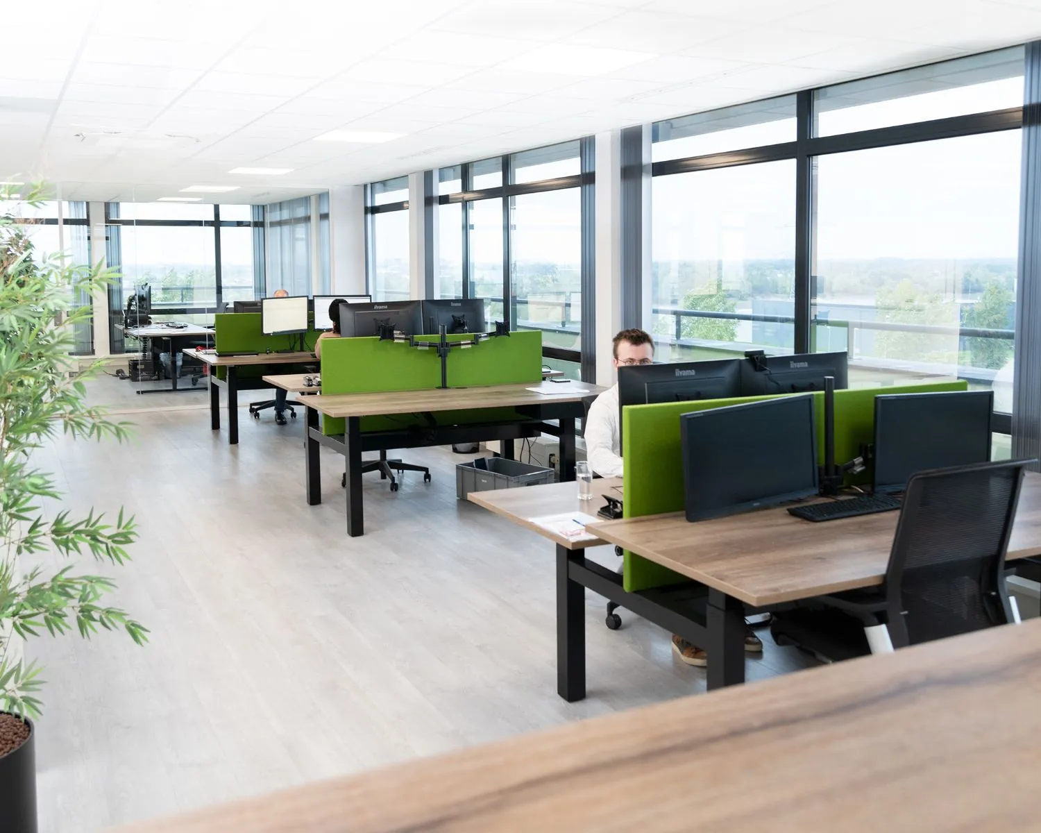 Moderne, lichte kantoorruimte met werkplekken en groene scheidingswanden aan de Pascallaan 60-78 in Lelystad.