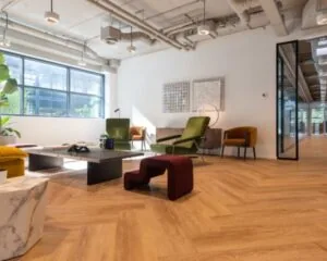 Moderne en stijlvol ingerichte kantoorruimte in het Coengebouw aan de Kabelweg 37 in Amsterdam met houten vloer, designmeubels en grote ramen.