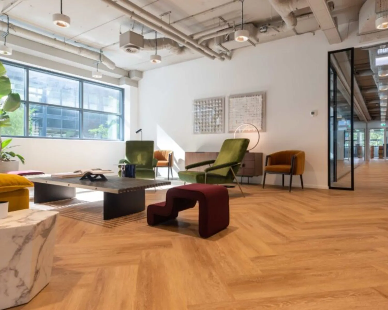 Moderne en stijlvol ingerichte kantoorruimte in het Coengebouw aan de Kabelweg 37 in Amsterdam met houten vloer, designmeubels en grote ramen.