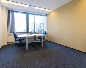 Twee bureaus met blauwe bureaustoelen in een lichte kantoorruimte aan de Gaetano Martinolaan 75-95 in Maastricht.