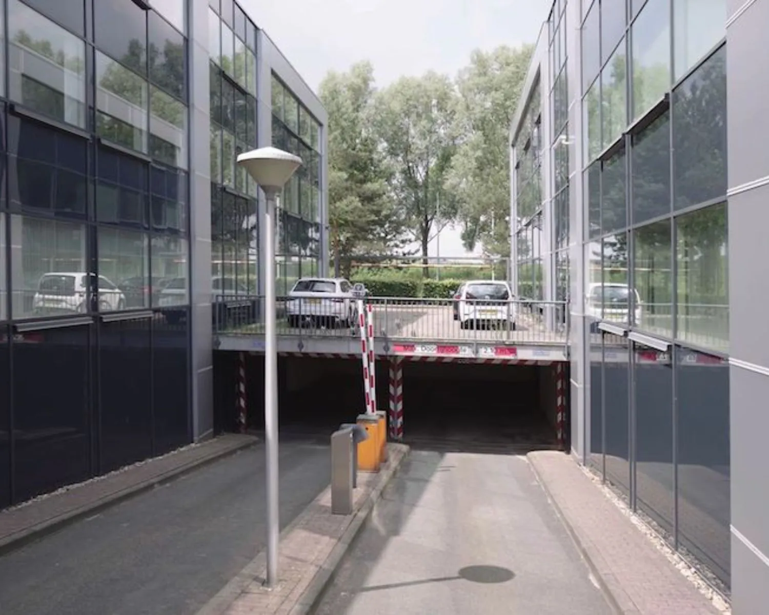 Ingang naar een ondergrondse parkeergarage tussen moderne kantoorgebouwen aan de Reeuwijkse Poort 114 in Reeuwijk.