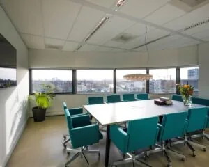 Moderne vergaderruimte met turquoise stoelen en uitzicht op Amsterdam, gelegen aan Rietlandpark 304.
