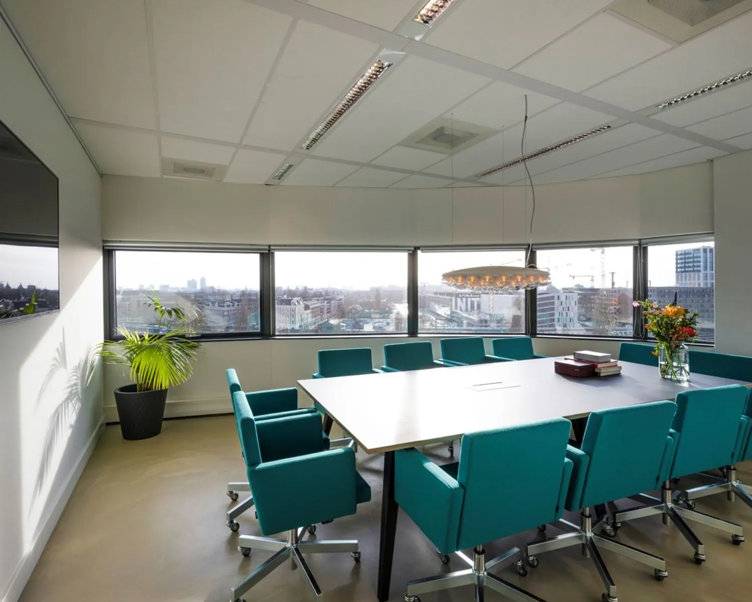 Moderne vergaderruimte met turquoise stoelen en uitzicht op Amsterdam, gelegen aan Rietlandpark 304.