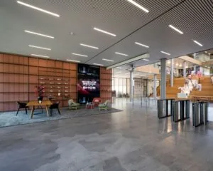 Moderne en ruime kantoorlobby aan de Taurusavenue 165 in Hoofddorp met zitgedeelte, houten traptribune en glazen toegangspoortjes.