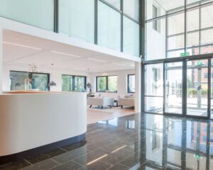 Moderne en lichte entreehal van een kantoorruimte aan de Bloemlaan 2 in Hoofddorp met zitgedeelte en glazen gevel.