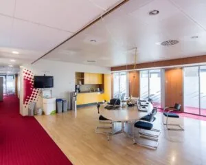 Moderne kantoorruimte aan de Kronenburgsingel 525 in Arnhem met vergadertafel, kitchenette en rode vloerbedekking.