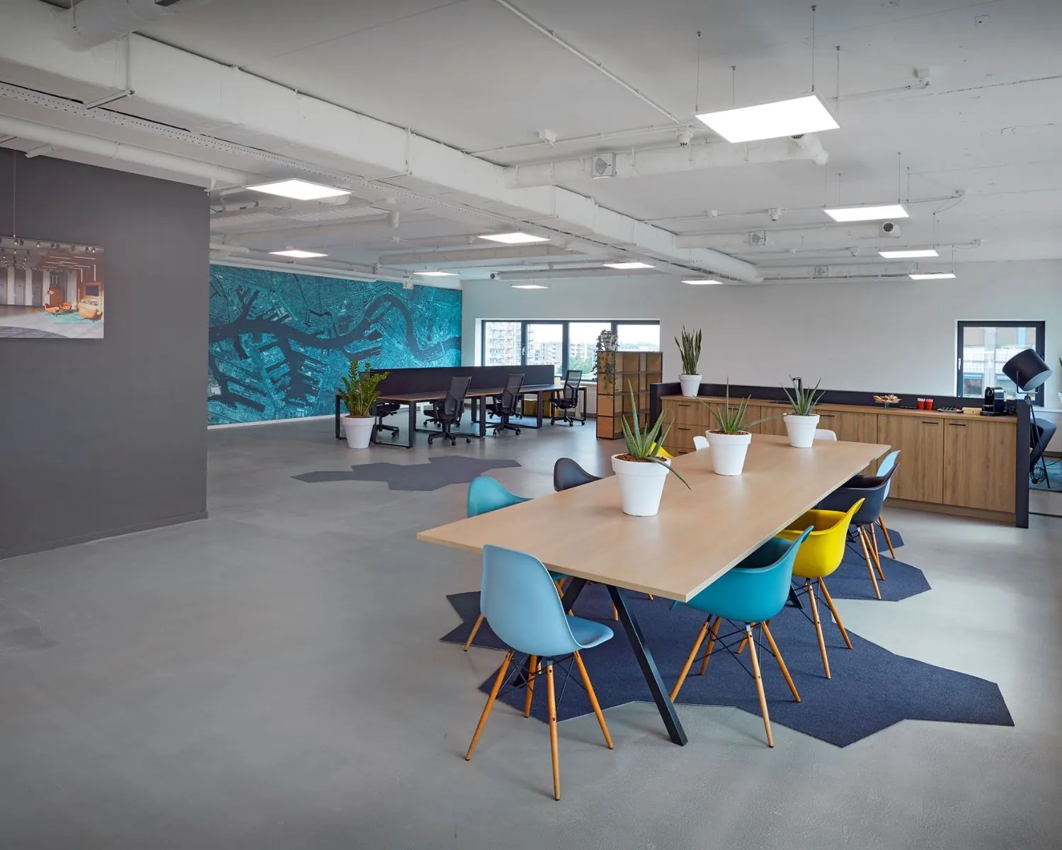 Moderne kantoorruimte met flexwerkplekken, een grote vergadertafel en kleurrijke stoelen op Prins Alexanderplein 5-21 in Rotterdam.