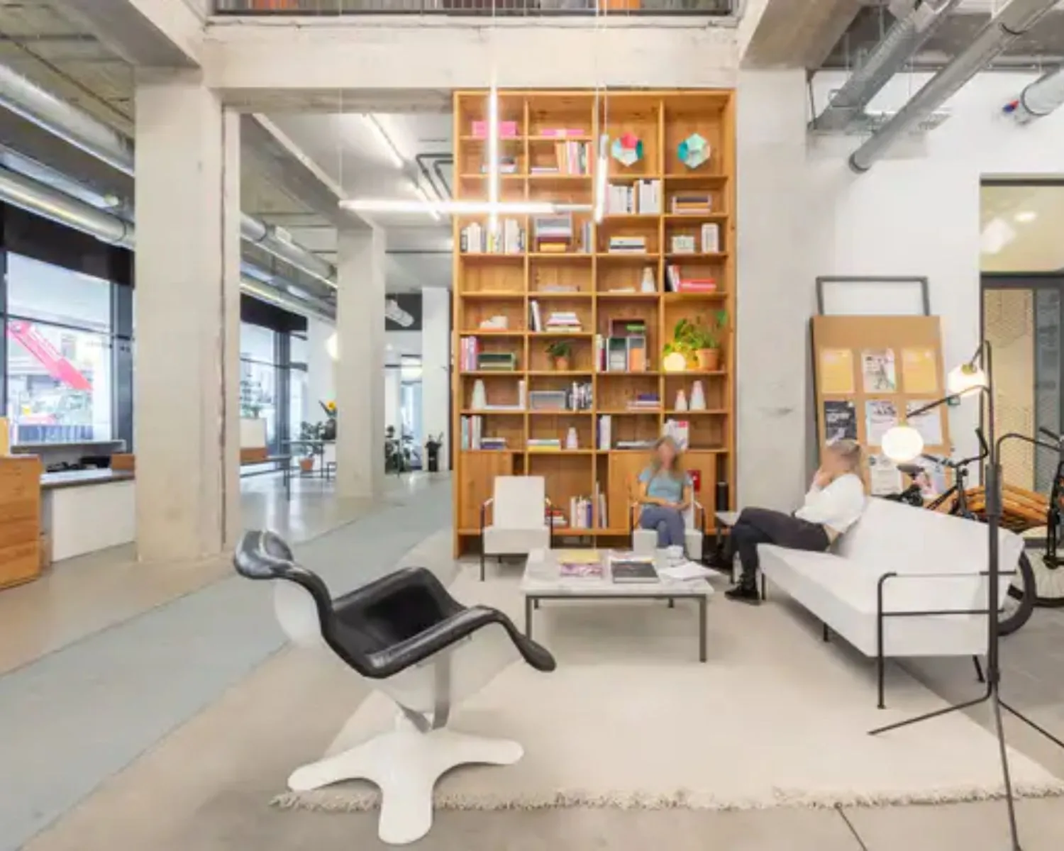 Moderne kantoorruimte aan de Vijzelstraat 60 in Amsterdam met hoge plafonds, een grote boekenkast en loungehoek.