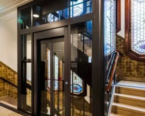 Moderne glazen lift in een trappenhuis met glas-in-loodramen in een kantoorpand aan de Westermarkt 2 in Amsterdam.