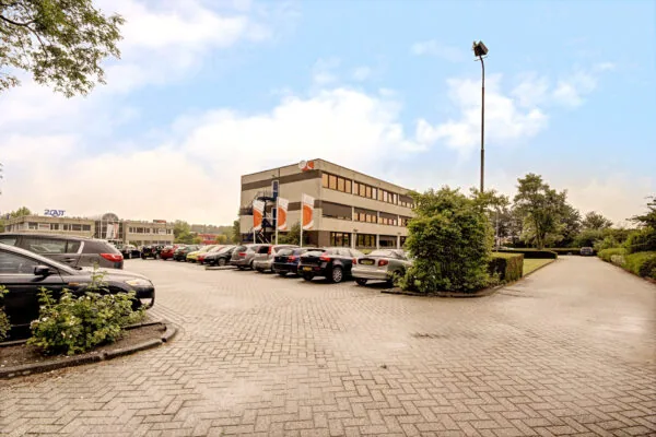 Kantoorpand aan de Maarssenbroeksedijk met parkeerplaats vol auto's op de voorgrond.