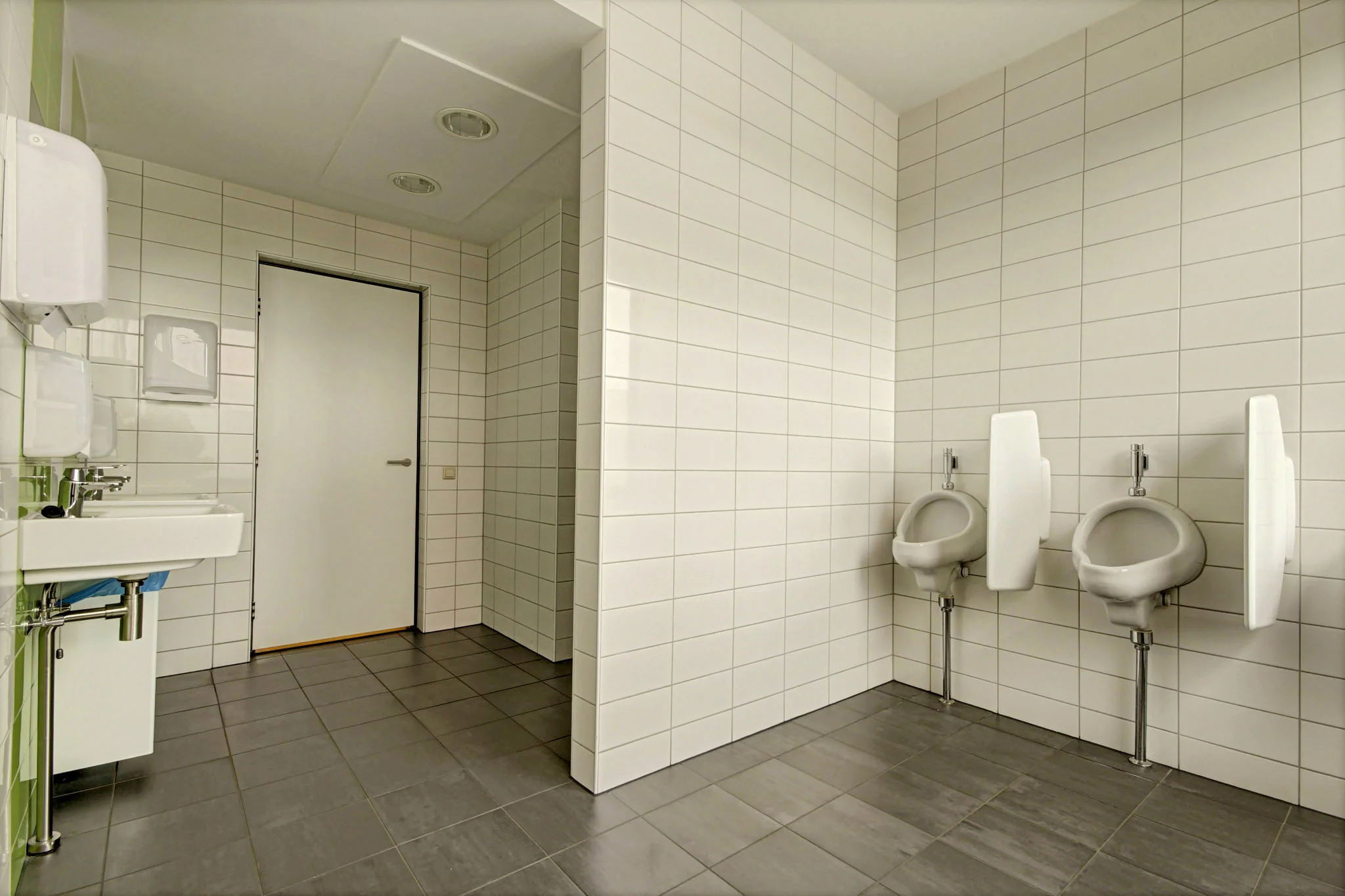Moderne, schone mannentoiletruimte met urinoirs, wastafels en witte wandtegels aan de Maarssenbroeksedijk.