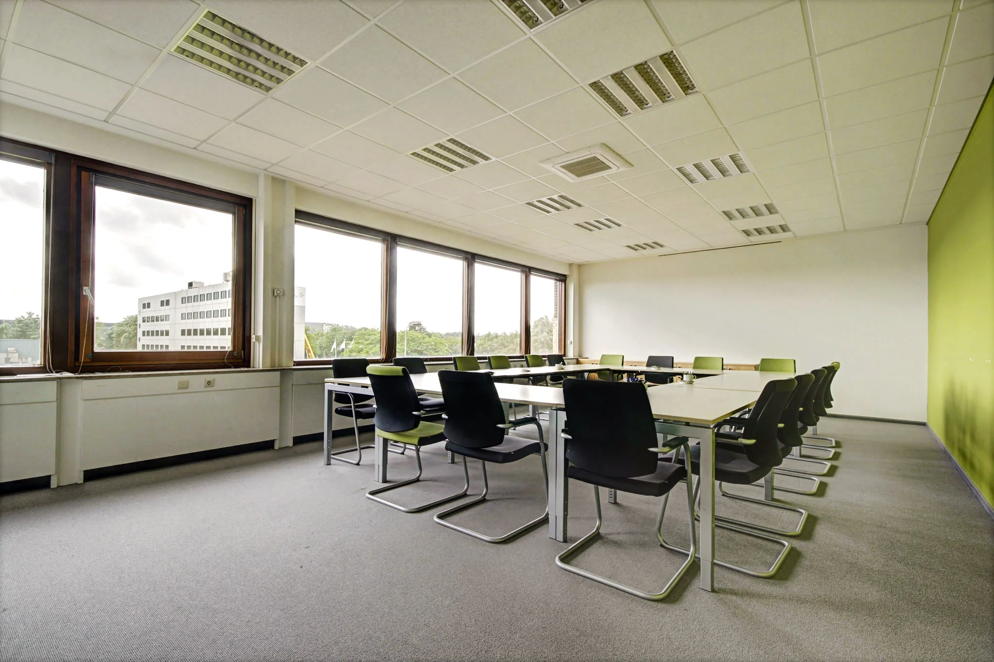 Vergaderruimte met moderne vergadertafels, zwarte stoelen en grote ramen aan de Maarssenbroeksedijk.