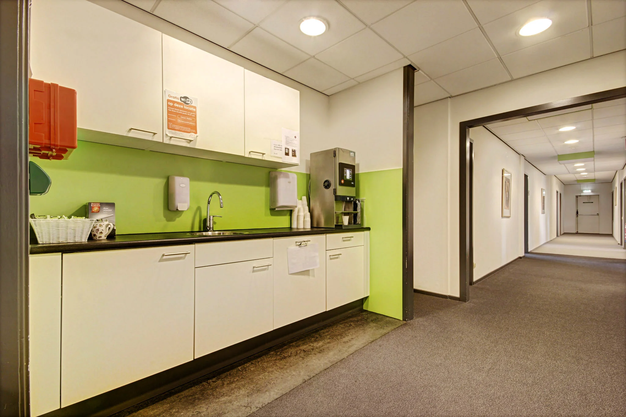 Kleine pantry met koffieautomaat en spoelbak in een gang van een kantoorpand aan de Maarssenbroeksedijk.