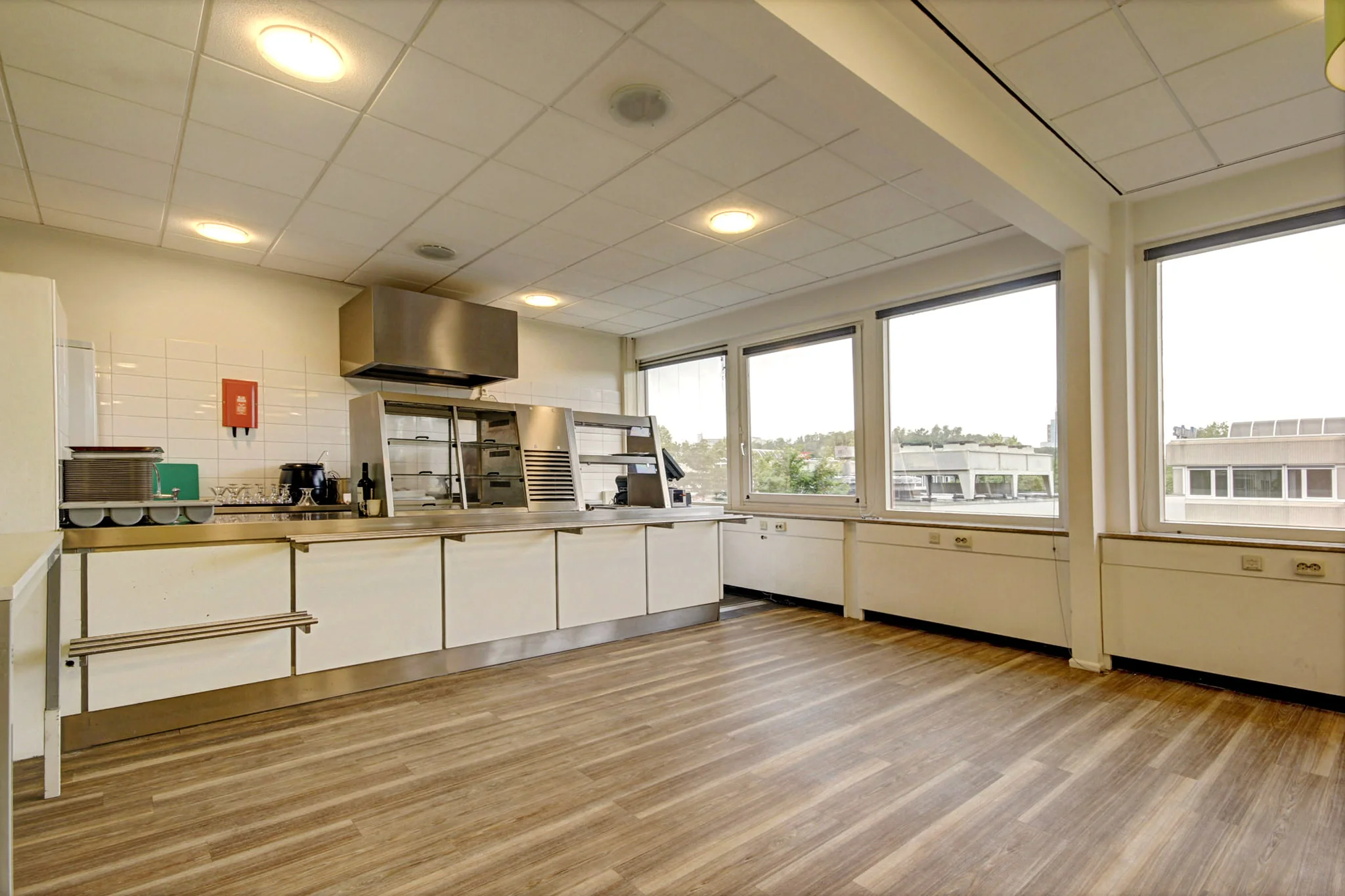 Moderne, lichte bedrijfskeuken aan de Maarssenbroeksedijk met grote ramen en houten vloer.