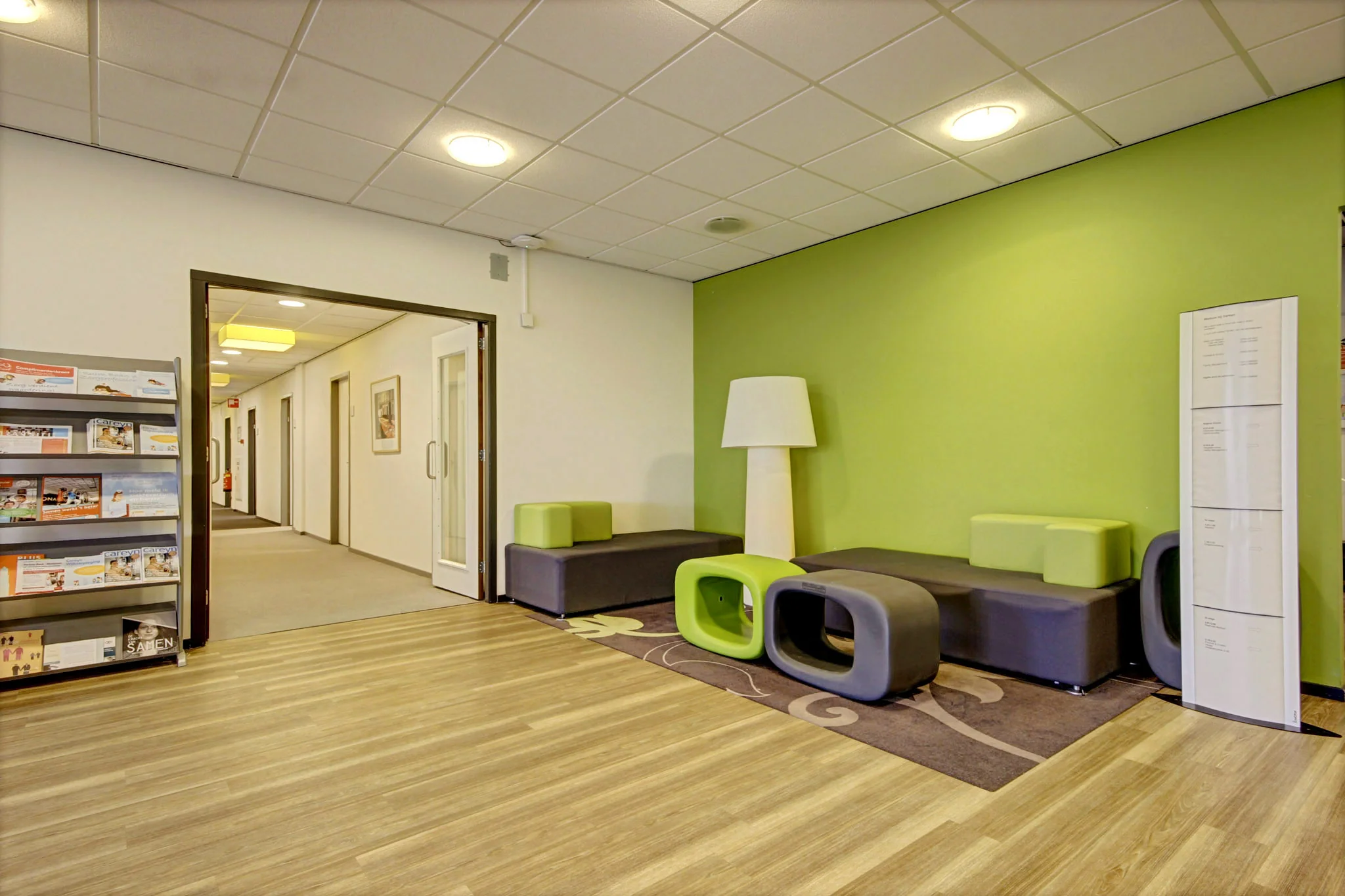 Wachtruimte met moderne zitmeubels en een groene accentmuur in een gebouw aan de Maarssenbroeksedijk.