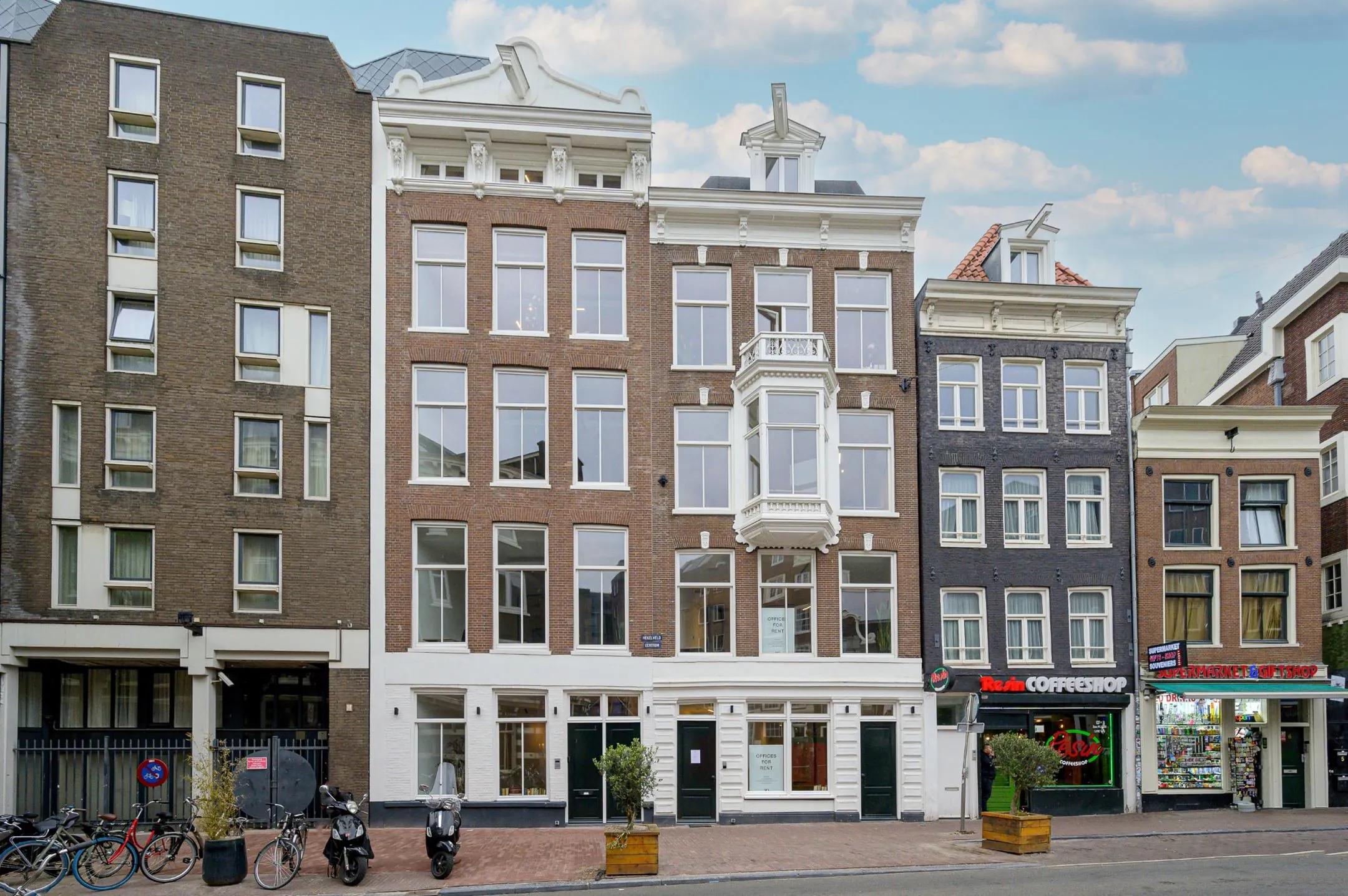 Voorgevel van een rij Amsterdamse panden aan de straatzijde, waaronder het gebouw 419_2160 met grote ramen en een erker.