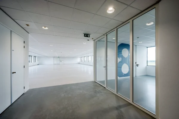 Een lege, ruime kantoorruimte met glazen wanden en witte muren.