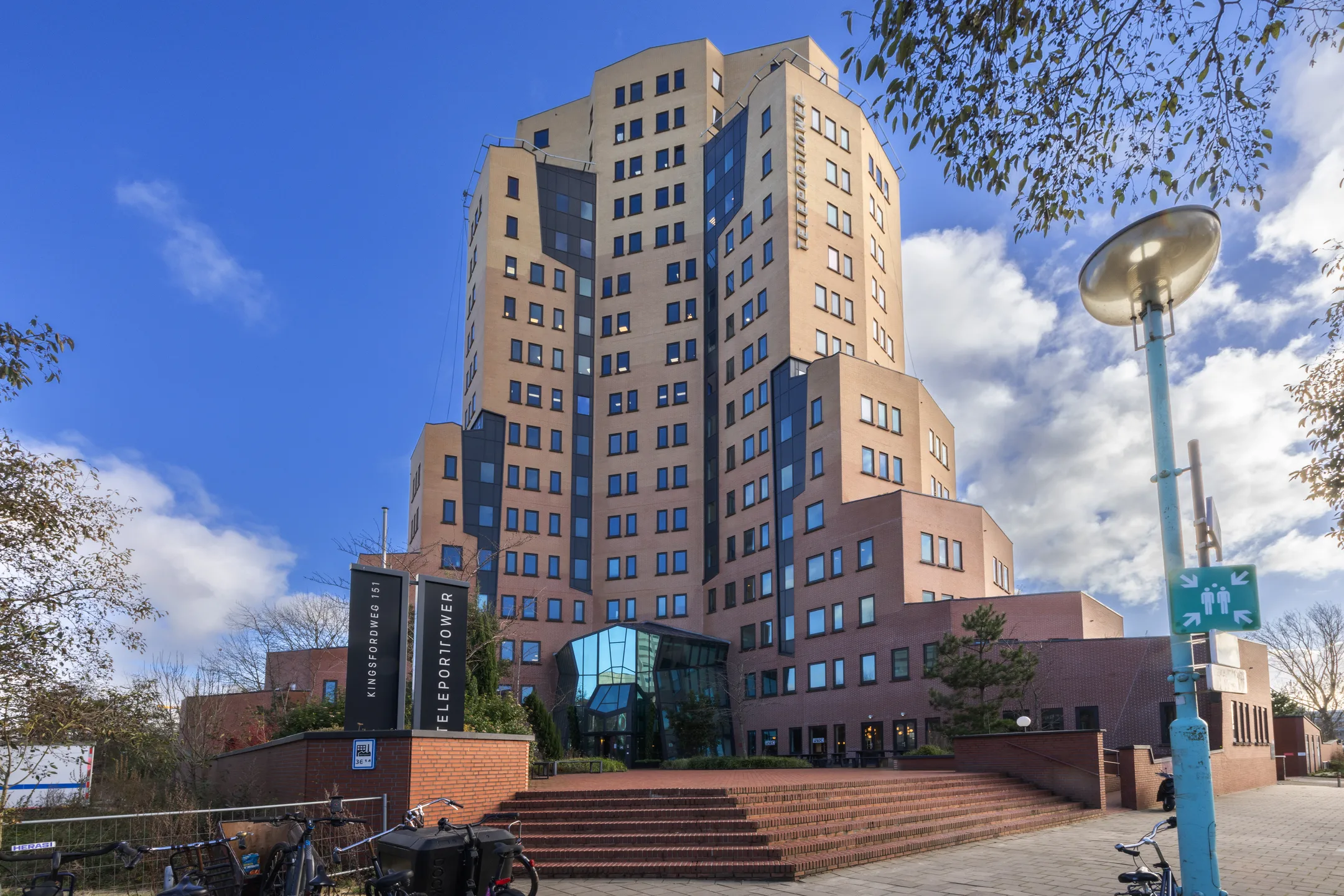 Een groot, modern gebouw genaamd Kingsfordweg 151, ook bekend als Teleport Tower, onder een heldere blauwe lucht.
