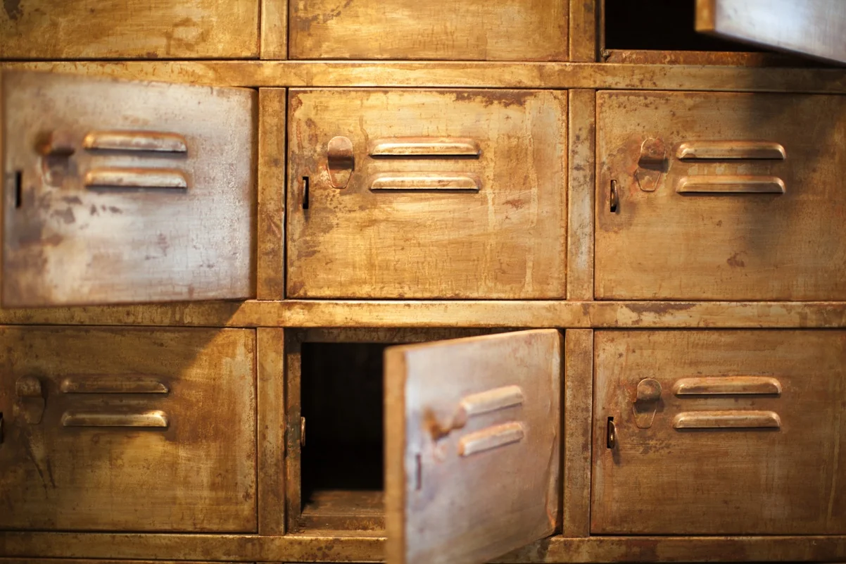 Close-up van een verweerde, metalen lockerwand met deels openstaande deurtjes.