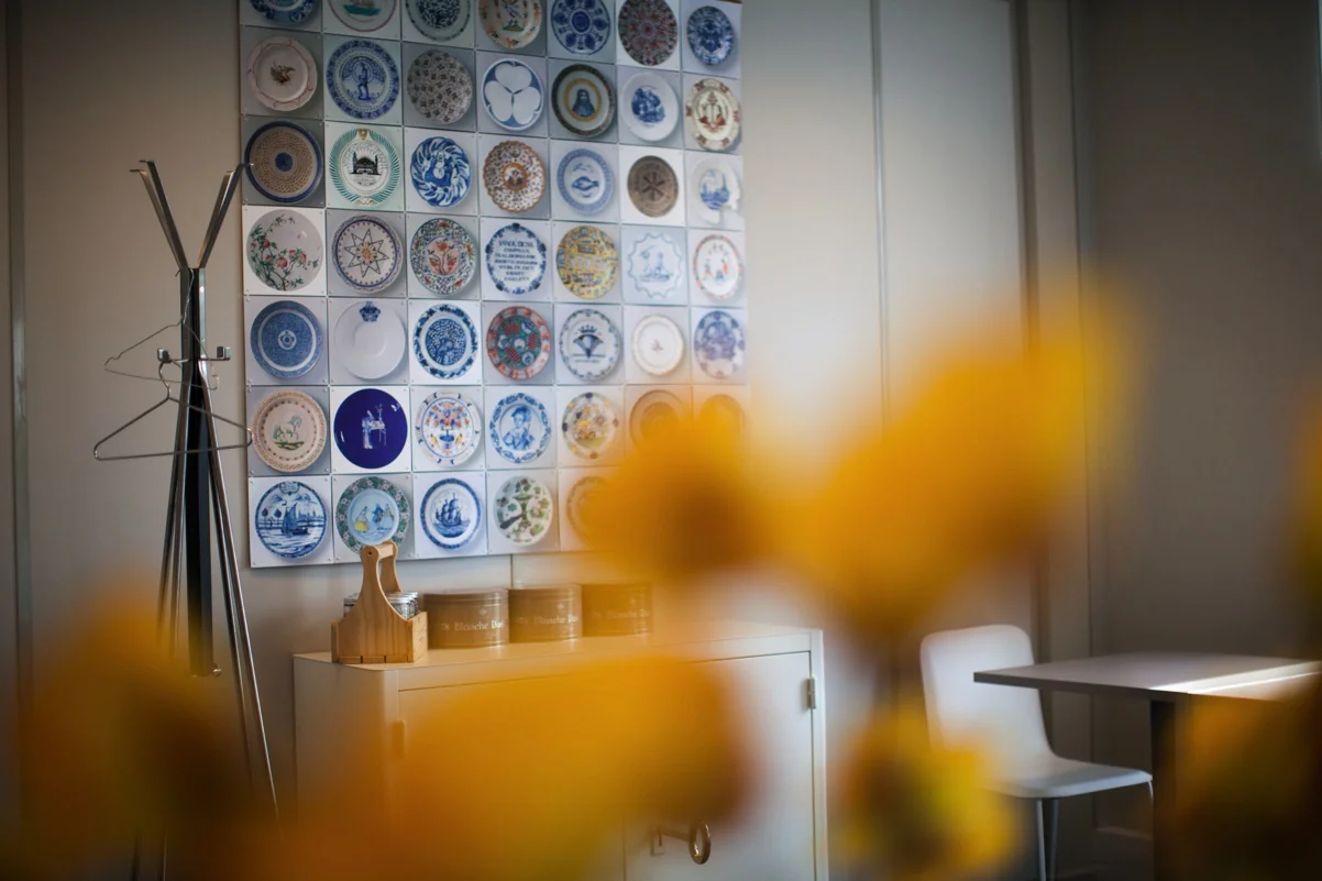 Binnenruimte met een wanddecoratie van sierborden, een kapstok, een witte kast en een tafel met stoel op Orteliuslaan.