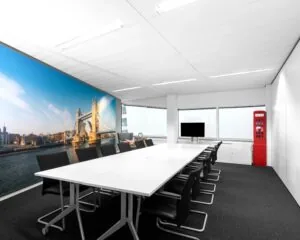 Vergaderruimte met lange tafel, zwart-witte stoelen, een muurposter van de Tower Bridge en een rode Engelse telefooncel.