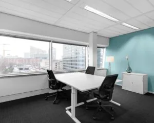 Moderne kantoorruimte met twee bureaus, bureaustoelen en uitzicht op een stedelijk zakendistrict.