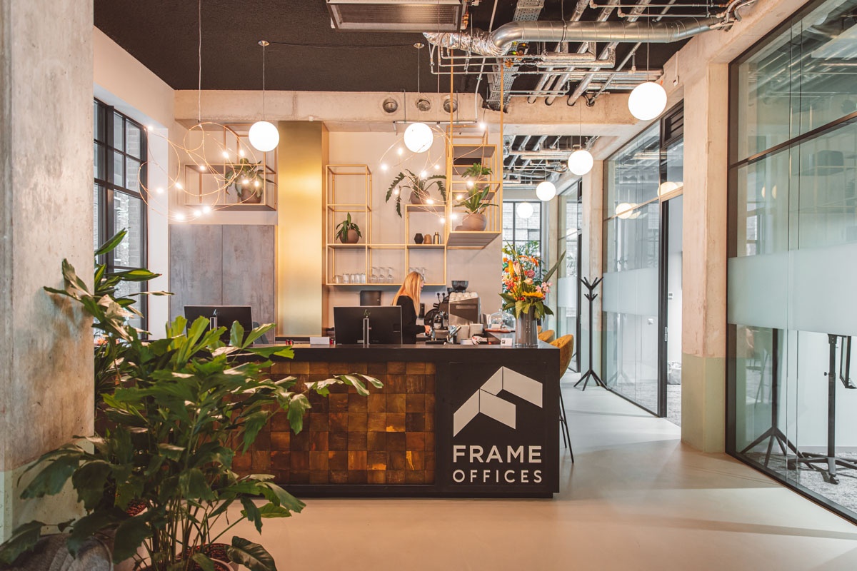 Ingang van Frame Offices met een moderne receptiebalie en groene planten.