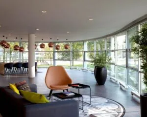 Modern ingerichte lounge met grote ramen, designmeubels en warme sfeerverlichting.