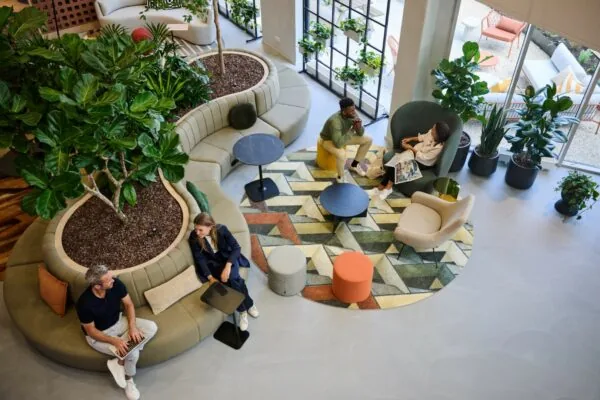 Moderne loungeruimte met planten, kleurrijke meubels en mensen in gesprek of aan het werk.