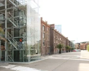 Moderne glazen entree naast een gerenoveerd kantoorgebouw aan de Vijf Werelddelen 69 in Rotterdam.