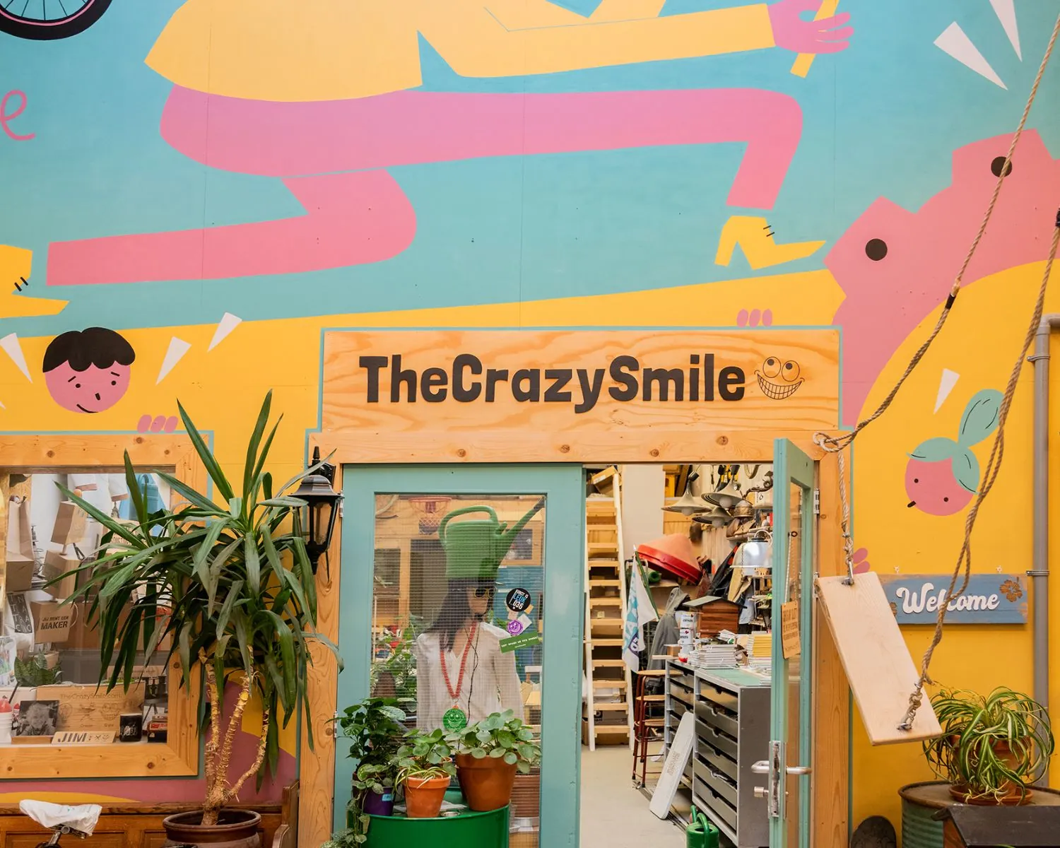 Ingang van creatieve werkruimte TheCrazySmile in Steiger 24 in Almere, met kleurrijke muurschildering en planten.