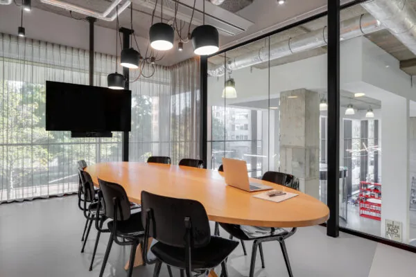 Moderne vergaderruimte in Utrecht Centraal met een ovale houten tafel, zwarte stoelen, hanglampen en een laptop op tafel.