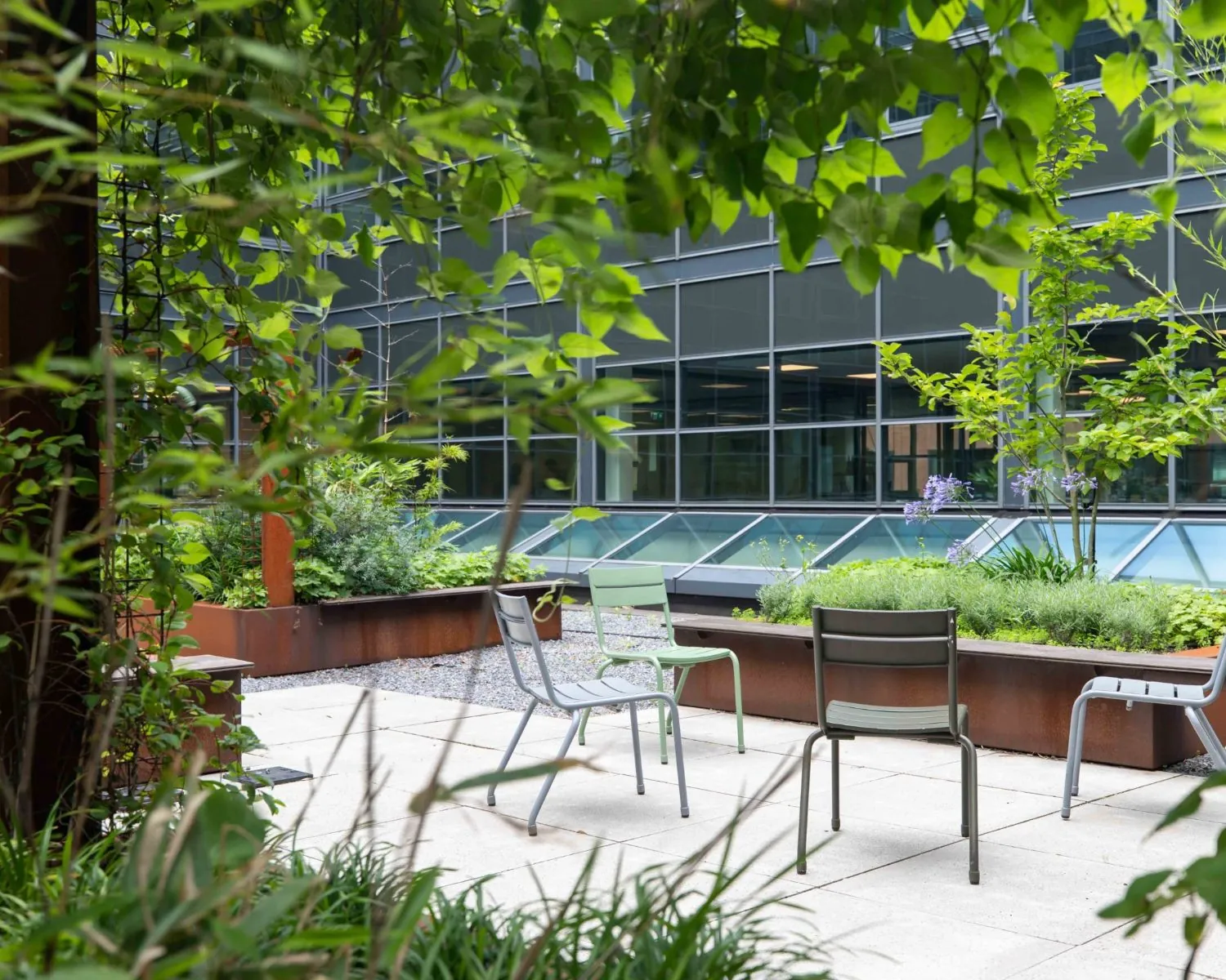 Groene binnentuin met stoelen bij het Coengebouw aan de Kabelweg 37 in Amsterdam.