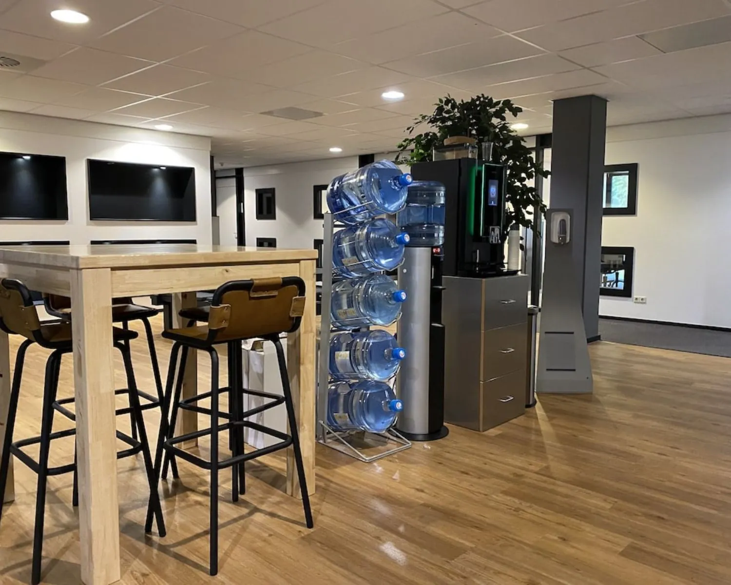 Moderne kantoorruimte in Elisabethhof, Leiderdorp met hoge tafel, barkrukken, watertankstation en koffiemachine.