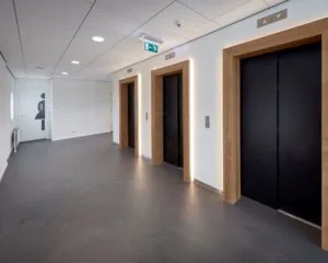 Moderne lifthal met drie liften en een toiletruimte in kantoorgebouw aan het Prins Alexanderplein 5-21 in Rotterdam.