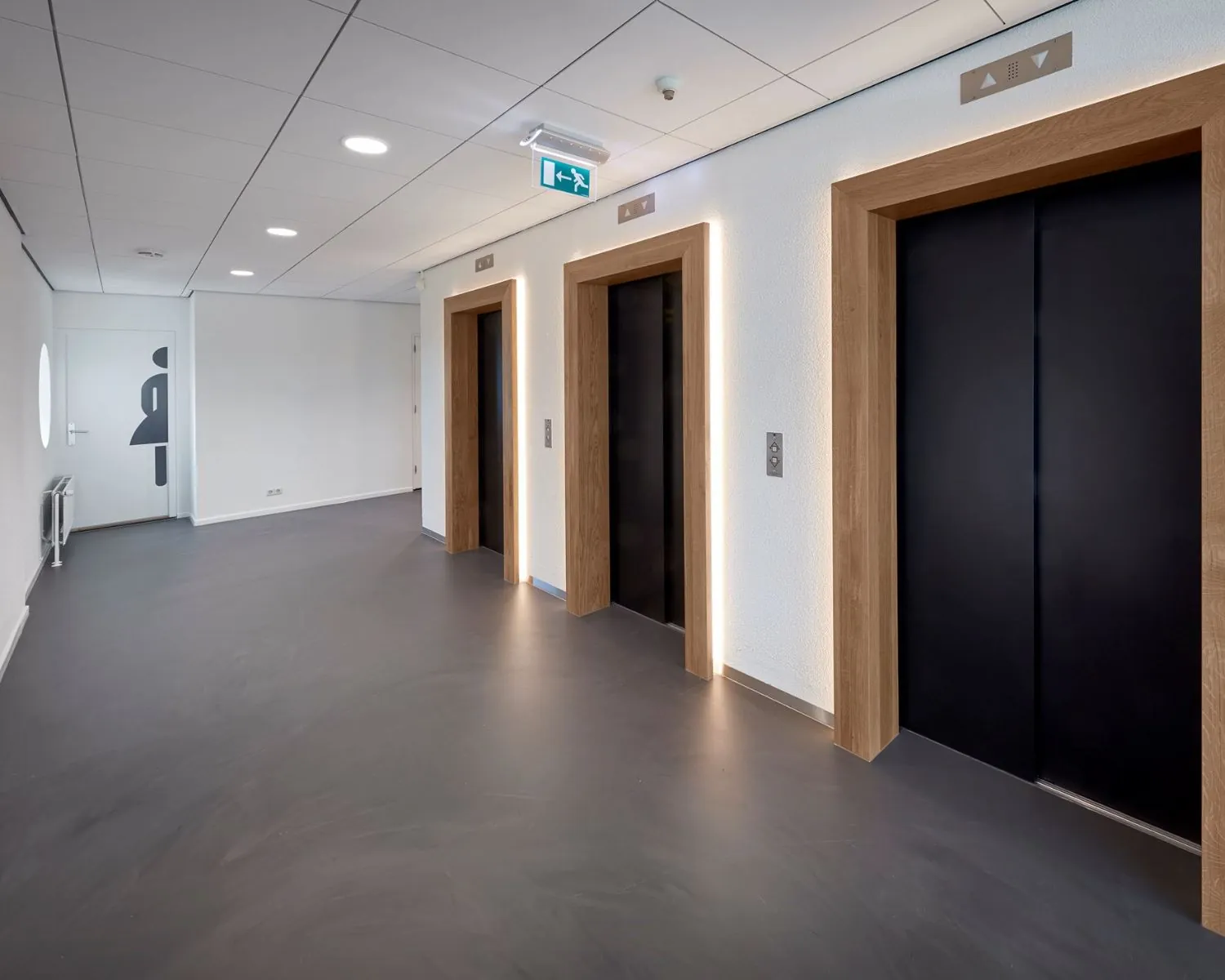 Moderne lifthal met drie liften en een toiletruimte in kantoorgebouw aan het Prins Alexanderplein 5-21 in Rotterdam.