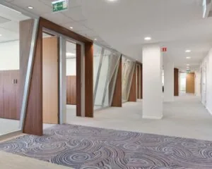 Moderne kantoorruimte aan de Treubstraat 1 in Rijswijk met glazen wanden, houten accenten en lichtgrijze vloerbedekking.